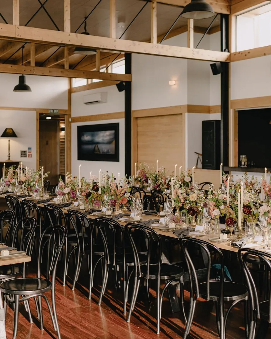 Long candlelit table set for a wedding inside the Kauri Bay dining hall